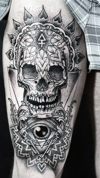 Tattoo of a skull with geometric and leaf designs on a person's upper leg