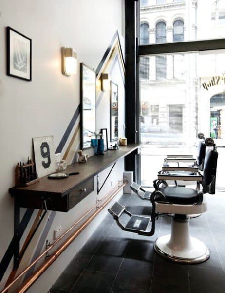 Contemporary barbershop with sleek black chairs, wall art, and minimalist wooden counters.
