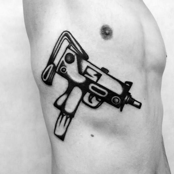 Bold black Uzi tattoo on the ribcage with thick outlines and a stylized design, creating a striking and graphic firearm depiction.