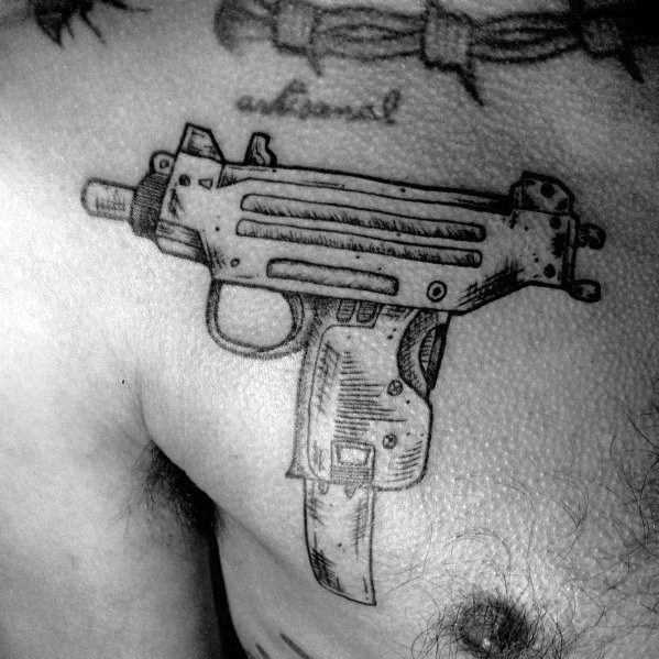 Realistic black and grey Uzi tattoo on the upper chest with fine line details and shading, giving it a rugged and worn firearm appearance.