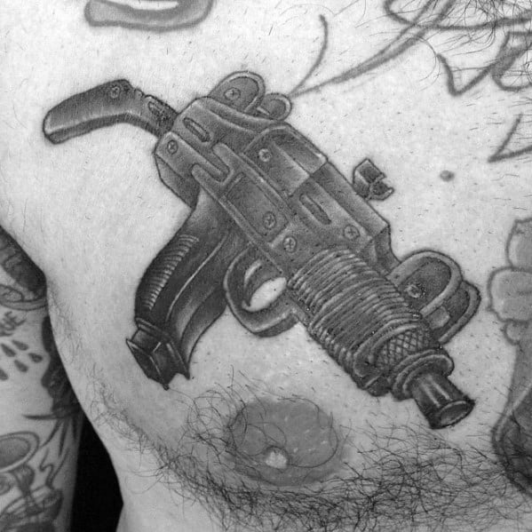 Realistic black and grey Uzi tattoo on the chest with intricate shading and fine details, creating a bold and lifelike firearm design.