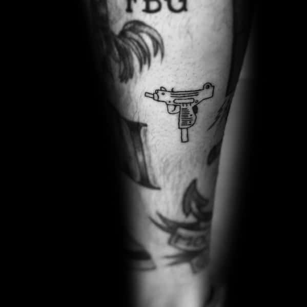 Small black outline Uzi tattoo on the leg with a minimalist design, featuring clean lines and subtle details for a simple yet bold look.