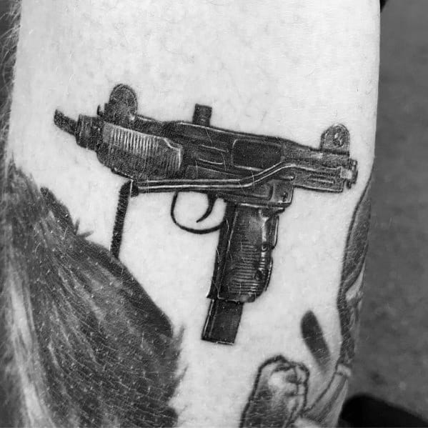 Realistic black and grey Uzi tattoo with intricate shading and fine details, creating a bold and lifelike firearm design on the skin.