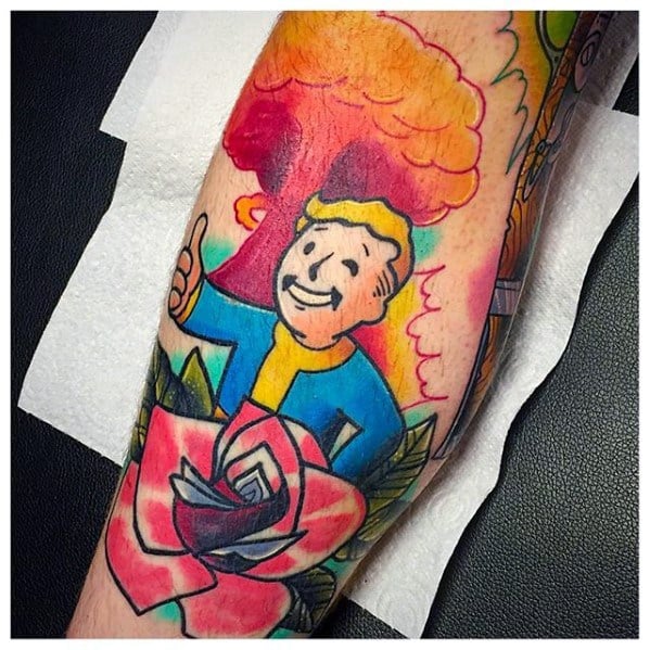 Vault Boy tattoo with a thumbs-up, standing in front of a red mushroom cloud and blooming pink rose for a bold Fallout-meets-nature look.