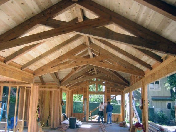 Garage construction with vaulted wooden beams, open framework, and natural lighting.
