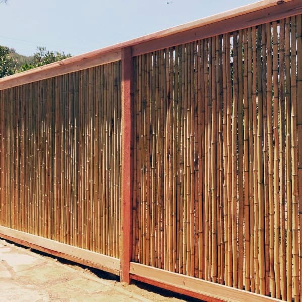 all bamboo fence with sturdy wooden frame along a sunlit backyard patio.