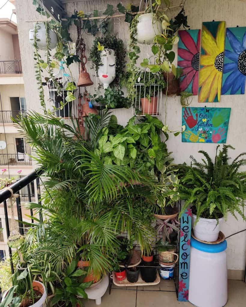 Balcony filled with various potted plants, hanging planters, and colorful wall art decor.