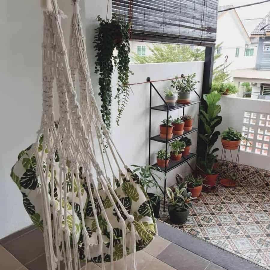 Balcony with a cozy swing chair, potted plants on shelves, and decorative tiled flooring.