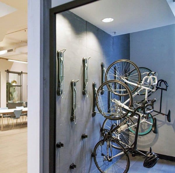 Vertical wall-mounted bike racks holding multiple bicycles in a modern indoor space.
