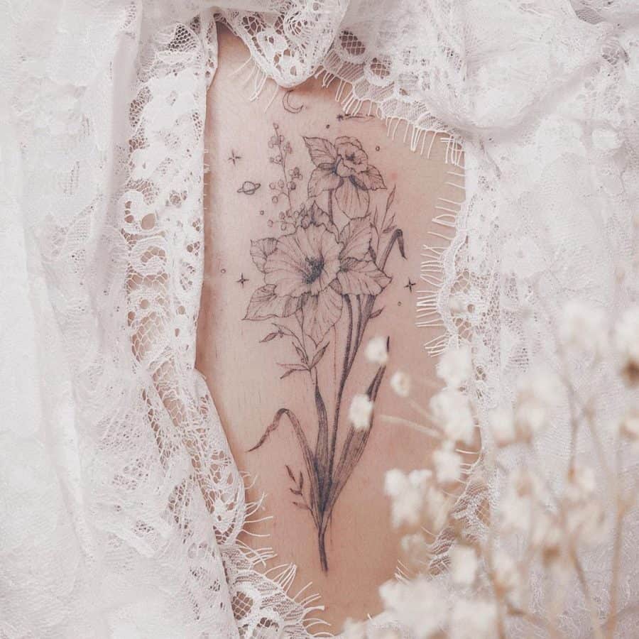 A beautiful, detailed black-and-white tattoo of daffodils, surrounded by small stars and floral elements, adding a whimsical and soft touch.
