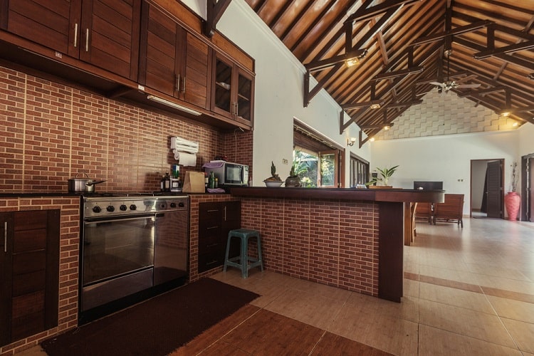 A luxury villa kitchen with a vaulted ceiling, wooden cabinetry, and a spacious layout, creating an airy and open atmosphere
