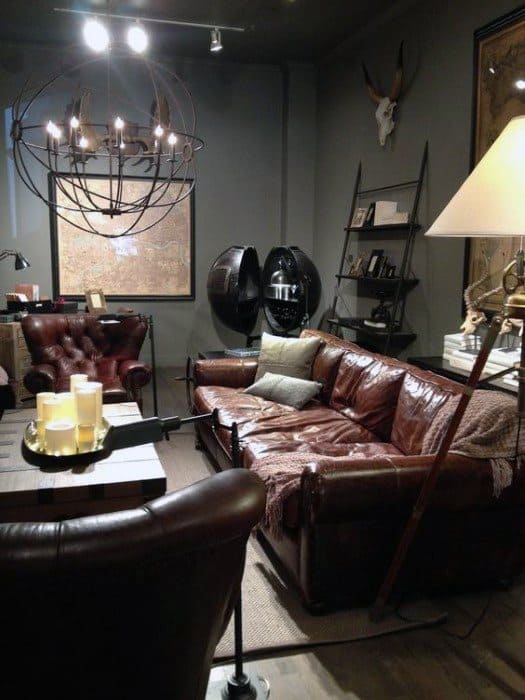 Cozy living room with brown leather sofas, a chandelier, candles, and wall decor