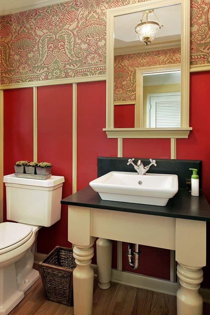 Classic bathroom with vintage wallpaper, red walls, and pedestal-style vanity.