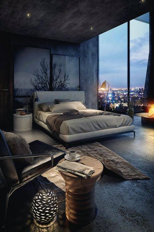 Modern bedroom with large window overlooking city lights, cozy bed, and fireplace