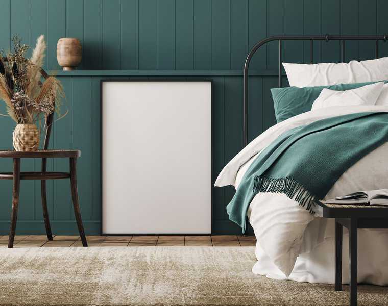 Vintage metal bed frame with green accent wall and rustic decor elements.