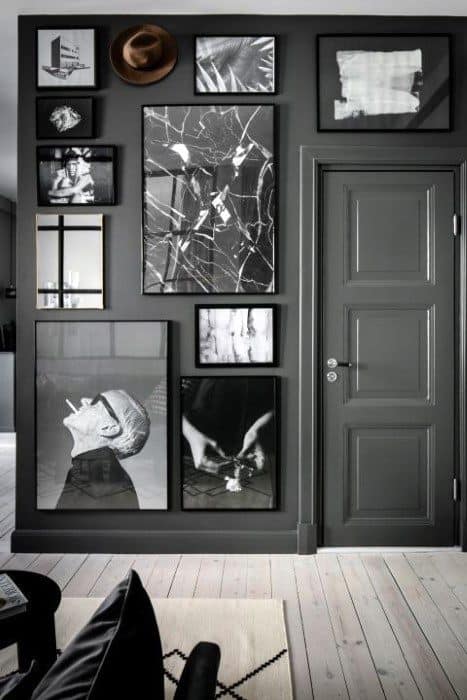 Vintage black and white photo gallery wall with various framed prints around a dark door.