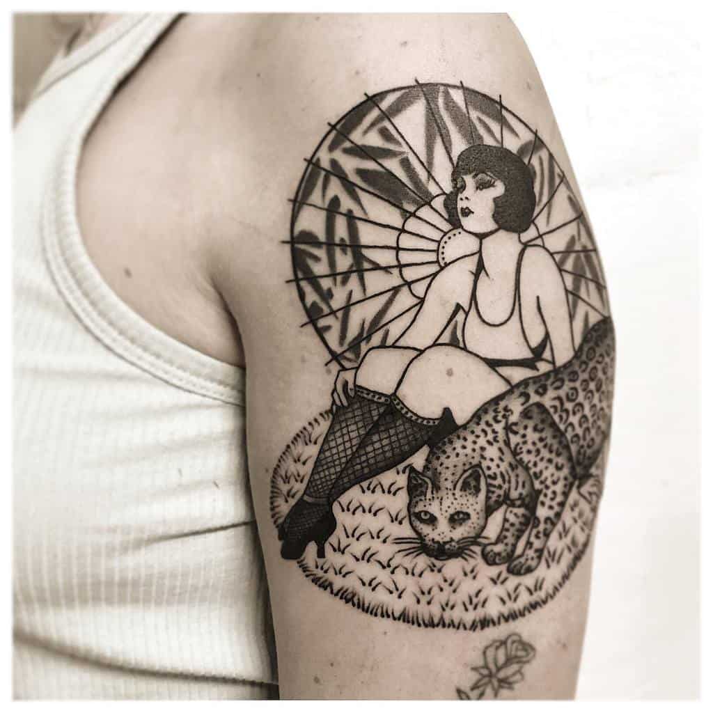A vintage-style tattoo featuring a woman in fishnet stockings sitting on a leopard, with a detailed parasol in the background, creating a timeless design.