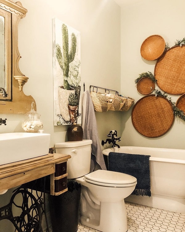A farmhouse-style bathroom with a sink, toilet, bathtub, woven baskets, and a cactus painting on the wall