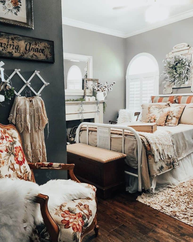Cozy farmhouse bedroom with vintage decor, a patterned armchair, and a bed with pillows and blankets in neutral tones