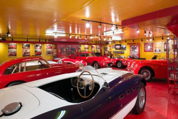 Vibrant garage featuring vintage Ferraris, classic cars, and bold red-yellow walls.