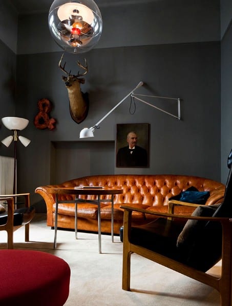 Cozy room with a leather sofa, wall-mounted deer head, portrait, and modern lighting