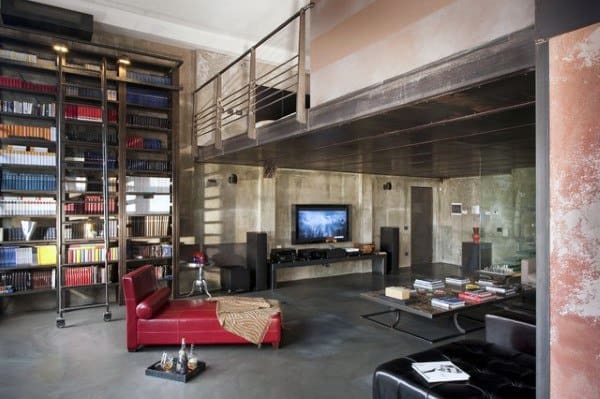 Industrial loft with floor-to-ceiling bookshelves, mezzanine, and cozy entertainment area.
