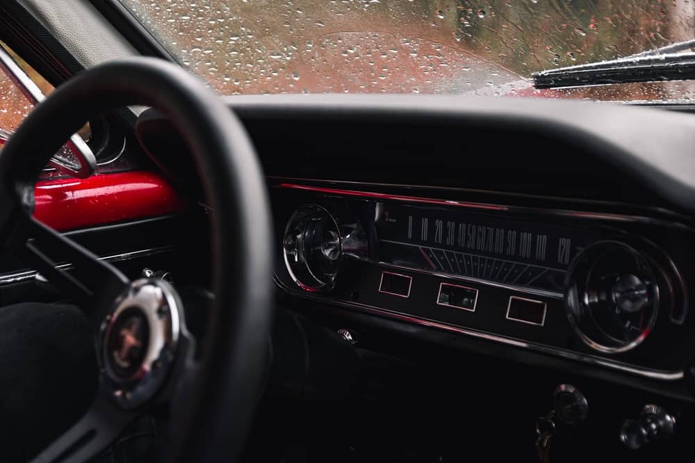 interior dashboard of a vintage mustang, with a wet windshield
