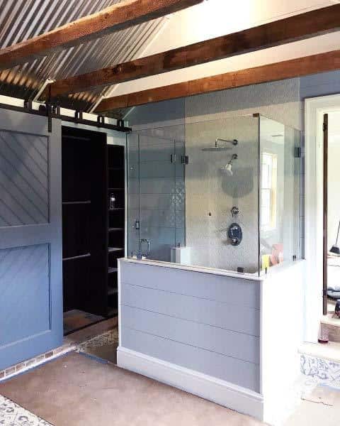 A modern, rustic bathroom with a glass-enclosed shower and sliding barn door