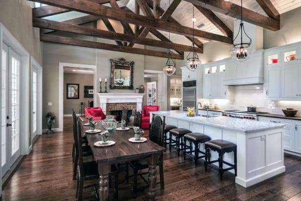 Rustic kitchen with white cabinets, wooden chairs, stainless steel appliances, and a central island.