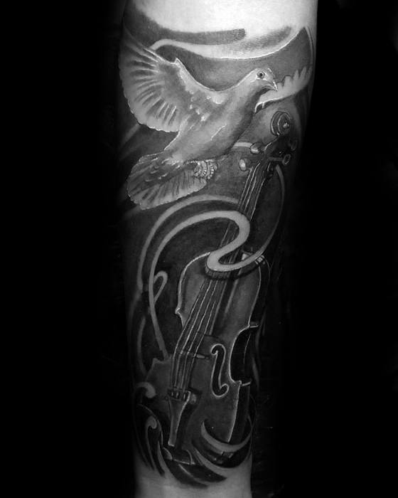 Black and gray tattoo of a violin with a dove soaring above it, surrounded by swirling abstract elements, symbolizing peace, freedom, and music.