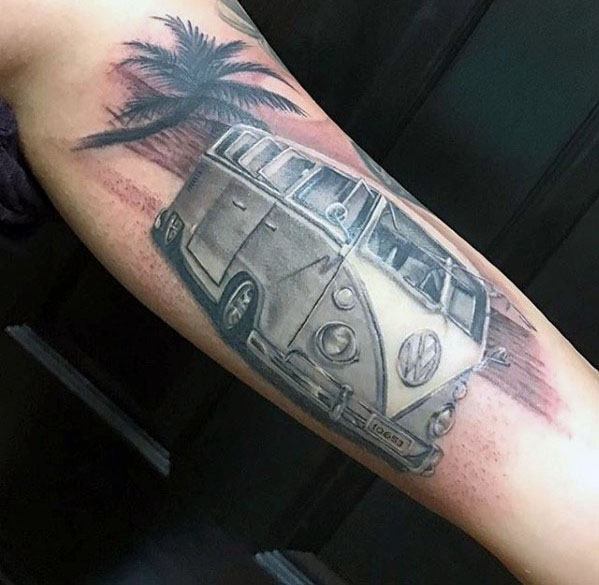 Volkswagen van tattoo with soft shading, set against a desert-like background with palm trees, inked on the inner arm.