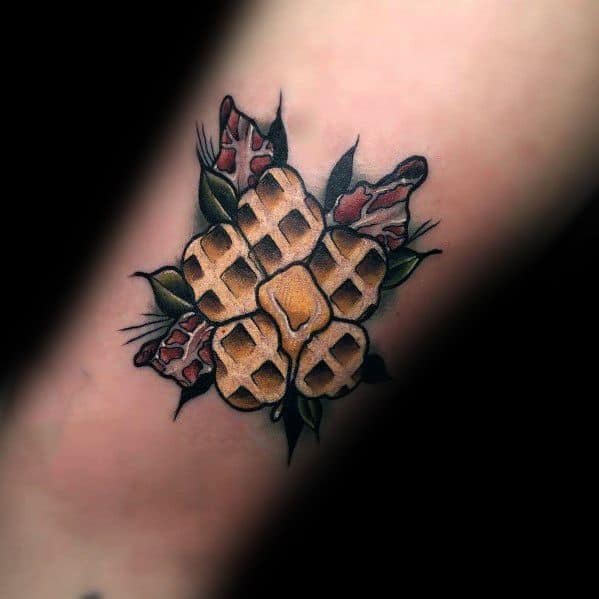 Traditional-style tattoo featuring a waffle designed like a flower, with butter in the center and bacon leaves, blending breakfast with bold classic art.