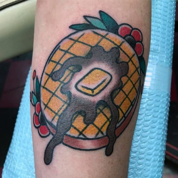 Traditional-style waffle tattoo with melted butter, dripping syrup, and floral accents, blending bold colors with a classic breakfast-inspired design.