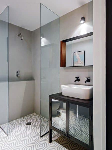 Modern corner bathroom with glass shower, geometric floor tiles, and vanity with a raised sink and wall-mounted faucet