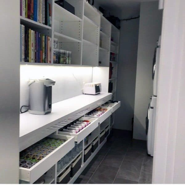 Walk-in pantry with open shelving, pull-out drawers, and under-cabinet lighting.