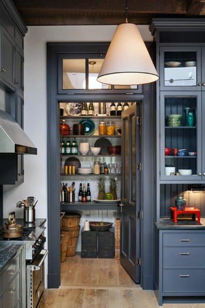 Walk-in pantry with dark cabinets, open shelves, and neatly arranged kitchen essentials.