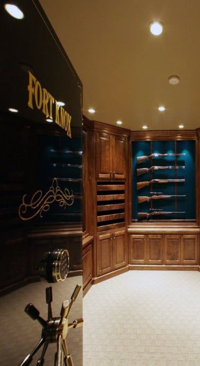 Walk-in gun safe with wooden cabinets, blue backing, and rifles displayed on racks.