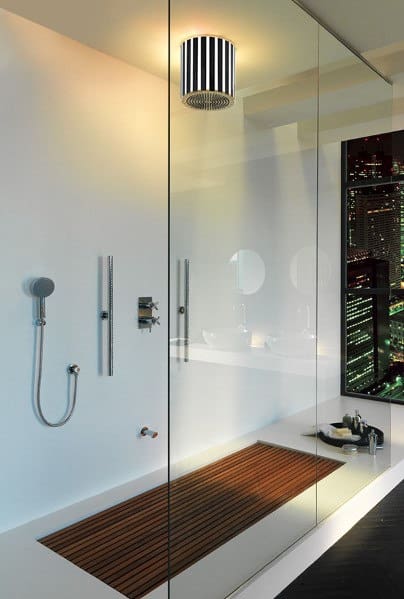 Modern bathroom with glass shower, wooden floor mat, and wall-mounted fixtures