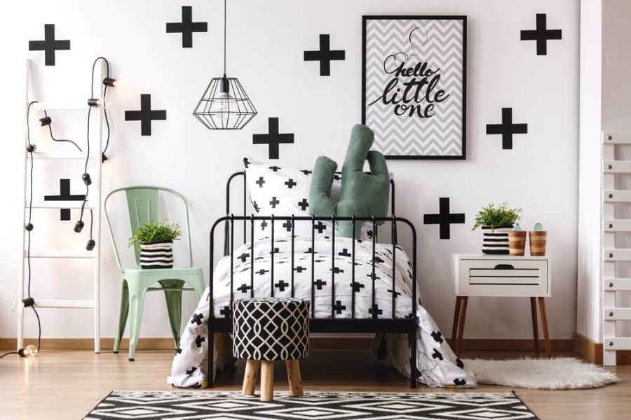 Black and white kids' bedroom with metal bed, wall patterns, and cactus decor.