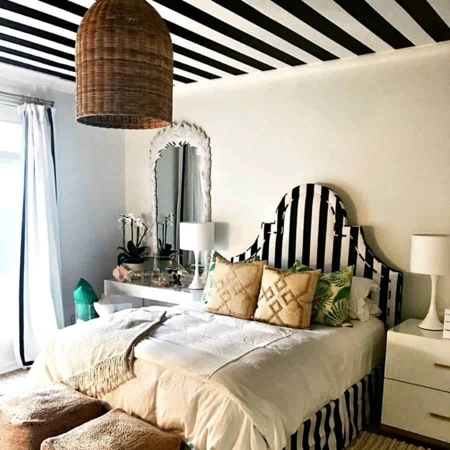 Stylish bedroom with striped black and white headboard, matching ceiling, and wicker decor.