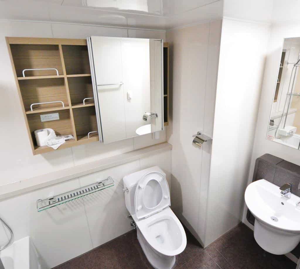 Bathroom with large wall cabinet above toilet and small round sink.