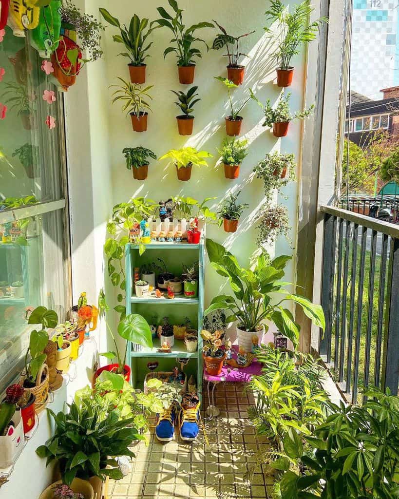 Wall balcony garden with potted plants, colorful decor, and a small green shelf.