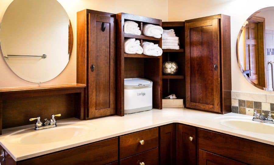 Bathroom with dark wood cabinets, open towel storage, and round mirrors.