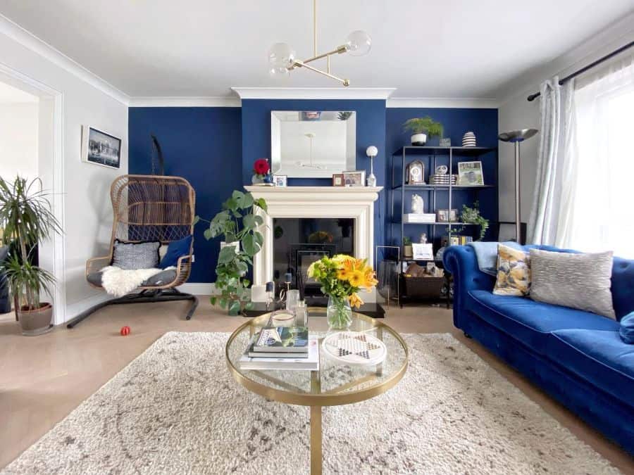 Contemporary living room with navy accent wall, blue sofa, and cozy decor elements.