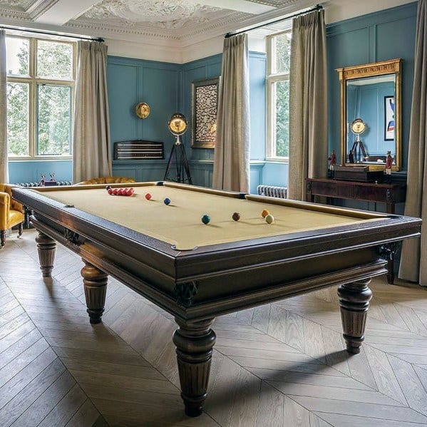 Sophisticated billiard room with blue walls, cream felt pool table, and elegant vintage decor.