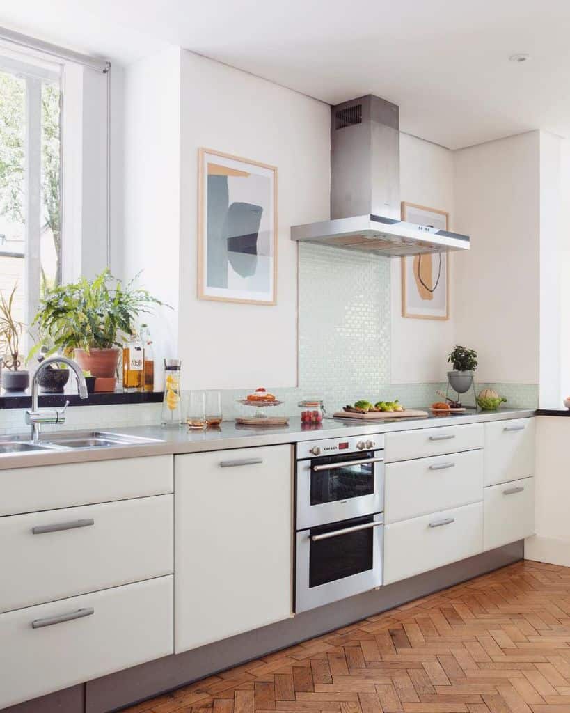 modern kitchen with white cabinets and pale green tile splashback framed wall art