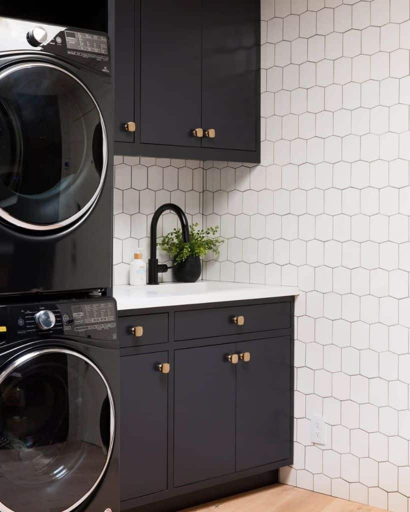 small modern laundry gray cabinets white tile wall stacked washer and dryer