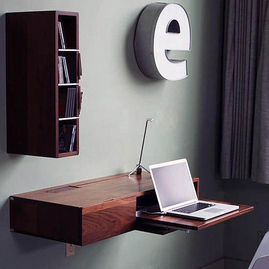 Modern wall-mounted desk with a laptop, shelving unit, and large letter "e" decoration