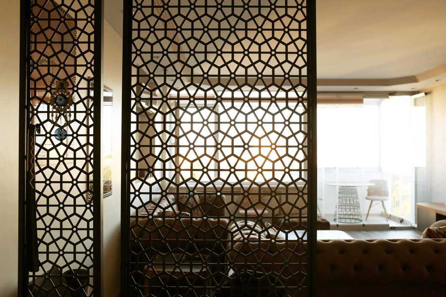 Intricately designed room divider with geometric patterns in a sunlit living room