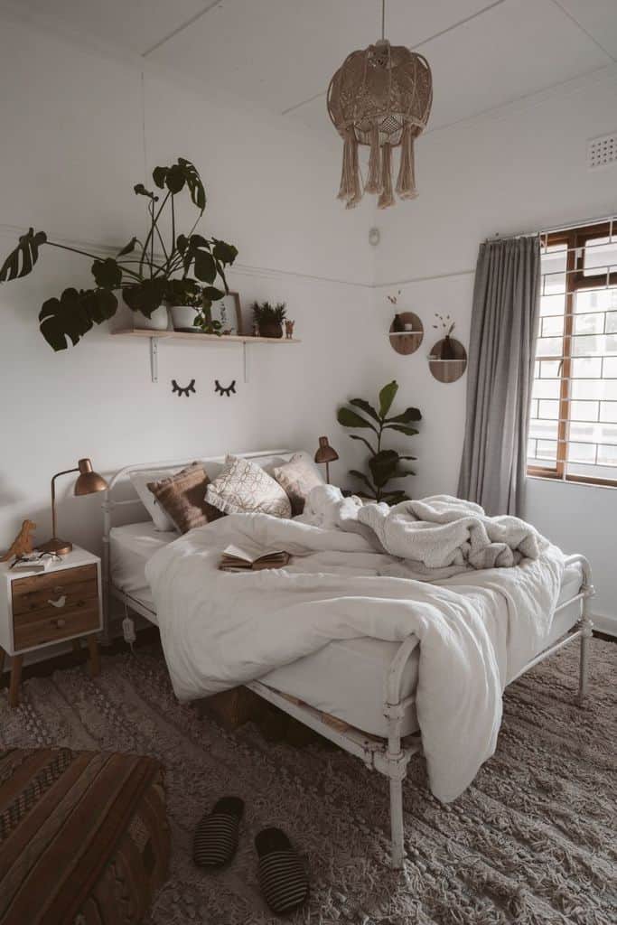 Cozy boho bedroom with macramé light, wall shelf plants, and layered neutral bedding.